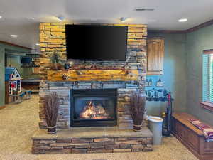 Detailed view of carpet floors, crown molding, a stone fireplace, and recessed lighting
