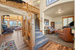 Staircase featuring a towering ceiling, arched walkways, and wood finished floors