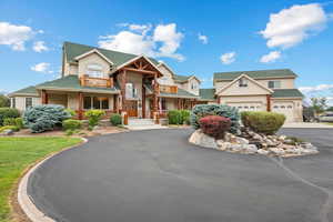 View of front of property featuring aphalt driveway, an attached garage, a balcony, a residential view, and stucco siding