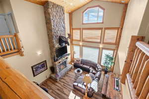 Living area featuring wood finished floors, high vaulted ceiling, a stone fireplace, plenty of natural light, and wood ceiling