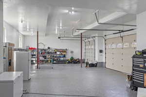 Garage featuring a garage door opener, freestanding refrigerator, and fridge