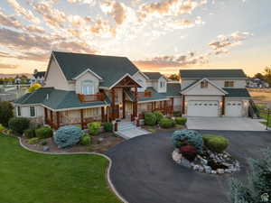 View of front of property featuring aphalt driveway, a yard, stone siding, a residential view, and stucco siding