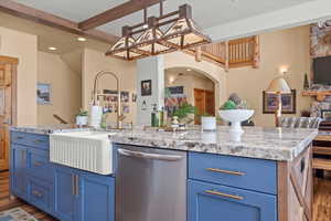 Kitchen with stainless steel dishwasher, dark wood-style flooring, a sink, and a center island with sink