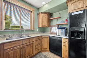 Kitchen featuring light countertops, a sink, black appliances, and open shelves