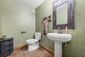 Bathroom with toilet, visible vents, and baseboards