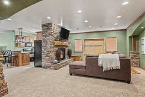 Living area featuring light colored carpet, a fireplace, recessed lighting, and ornamental molding