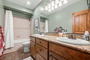 Full bathroom with toilet, double vanity, a sink, and shower / bath combo with shower curtain