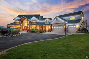 View of front of home with a balcony, a garage, driveway, a lawn, and stucco siding