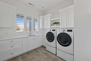 Washroom featuring cabinets, sink, and washing machine and clothes dryer