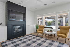 Living area featuring ceiling fan, a large fireplace, and light hardwood / wood-style floors