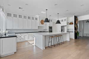 Kitchen with white cabinetry, a kitchen island, light hardwood / wood-style flooring, and appliances with stainless steel finishes