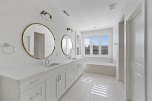 Bathroom with tile patterned flooring, vanity, and a relaxing tiled tub