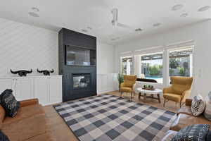 Living room featuring ceiling fan, a large fireplace, and light wood-type flooring