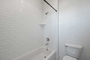 Bathroom with tiled shower / bath combo and toilet