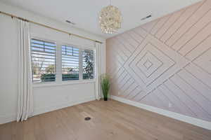 Unfurnished room with a notable chandelier and light wood-type flooring