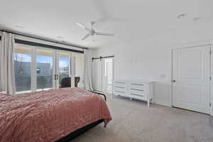 Carpeted bedroom with a barn door, access to outside, ceiling fan, and french doors