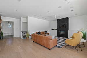 Living room with a large fireplace, ceiling fan, and light wood-type flooring