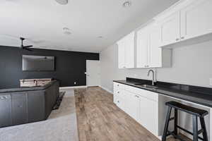 Kitchen with white cabinetry, sink, ceiling fan, and light hardwood / wood-style flooring