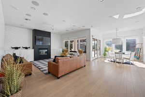 Living room with ceiling fan, plenty of natural light, a fireplace, and light hardwood / wood-style floors