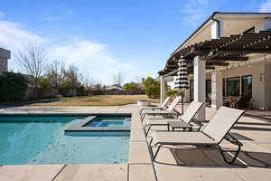 View of pool featuring a pergola, a lawn, a patio, and an in ground hot tub