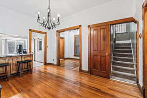 Interior space with wood-type flooring, a notable chandelier, and crown molding