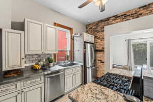 Kitchen with ceiling fan, brick wall, stainless steel appliances, and sink