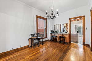 Dining room with ornamental molding, dark hardwood / wood-style floors, and an inviting chandelier