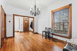 Entrance foyer with ornamental molding, light hardwood / wood-style flooring, and a notable chandelier