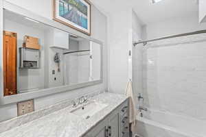 Bathroom with tiled shower / bath combo and vanity