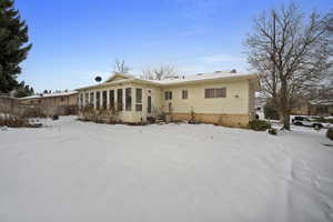 Snow covered rear of property featuring brick siding