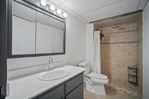 Bathroom featuring tiled shower, toilet, tile patterned floors, a textured ceiling, and vanity