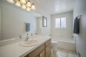 Bathroom with visible vents, toilet, a textured ceiling, vanity, and a bath