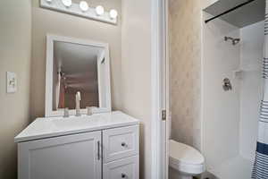 Bathroom featuring toilet, vanity, and a shower with curtain