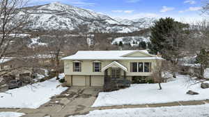 Bi-level home with driveway, an attached garage, and a mountain view