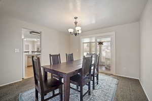 Dining room with light carpet, visible vents, baseboards, an inviting chandelier, and a textured ceiling