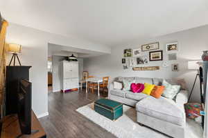 Living room with dark wood-type flooring and baseboards