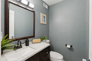 Bathroom featuring toilet, vanity, and visible vents