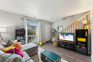 Living room with stairs, visible vents, baseboards, and wood finished floors