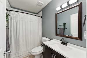 Bathroom with visible vents, vanity, toilet, and shower / bath combo with shower curtain