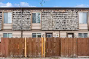 View of side of property featuring fence and mansard roof