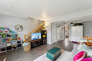 Living room featuring stairway, wood finished floors, visible vents, and baseboards