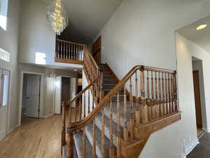 Staircase featuring a high ceiling, an inviting chandelier, and hardwood / wood-style floors