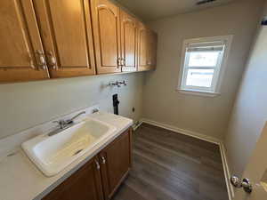 Laundry area with hookup for a washing machine, sink, cabinets, and dark wood-type flooring