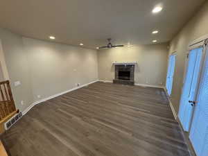 Unfurnished living room featuring recessed lighting, visible vents, a tiled fireplace, dark wood-type flooring, and ceiling fan