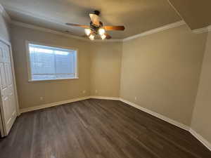 Unfurnished bedroom featuring ceiling fan, crown molding, a textured ceiling, and dark hardwood / wood-style flooring