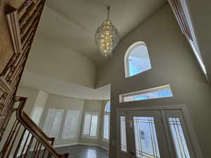 Foyer with hardwood / wood-style flooring, high vaulted ceiling, and an inviting chandelier