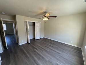 Unfurnished bedroom with ceiling fan, a closet, dark hardwood / wood-style flooring, and a textured ceiling