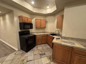 Kitchen featuring sink, a raised ceiling, and black appliances