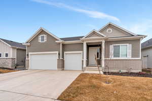 View of front of home with driveway, brick siding, an attached garage, and a front yard