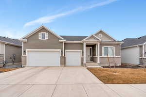 Craftsman-style house featuring a garage, driveway, and brick siding